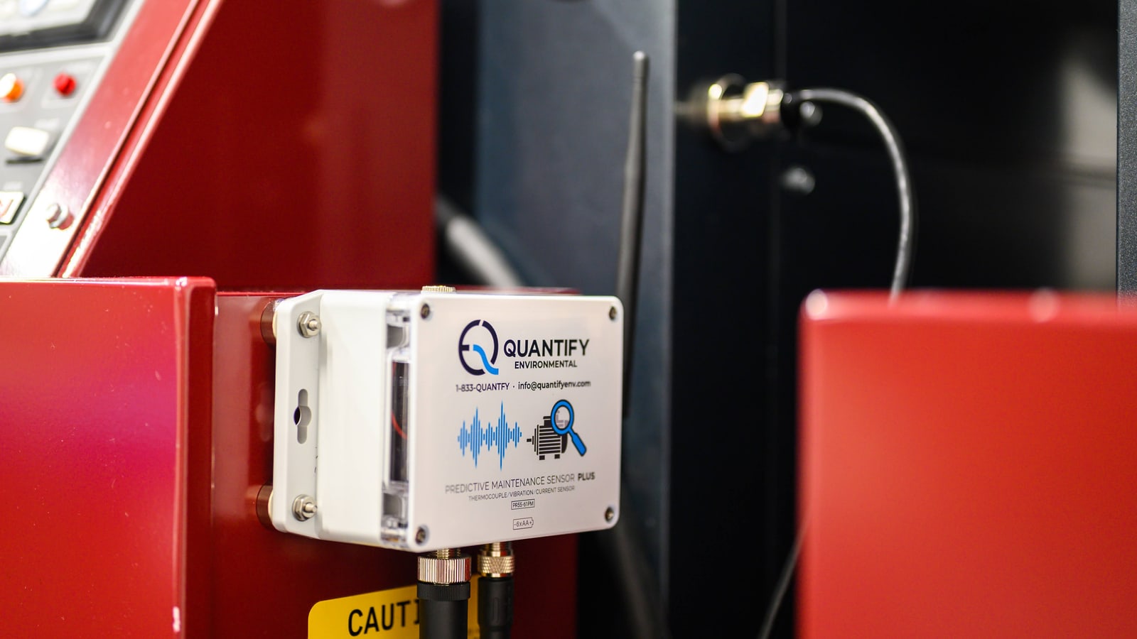 A Quantify predictive maintenance sensor mounted on a red compressor package in a plant room